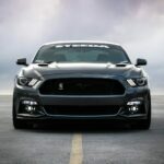 A dark grey Ford Mustang parked on an empty asphalt parking lot