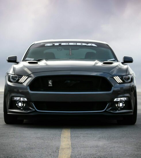 A dark grey Ford Mustang parked on an empty asphalt parking lot